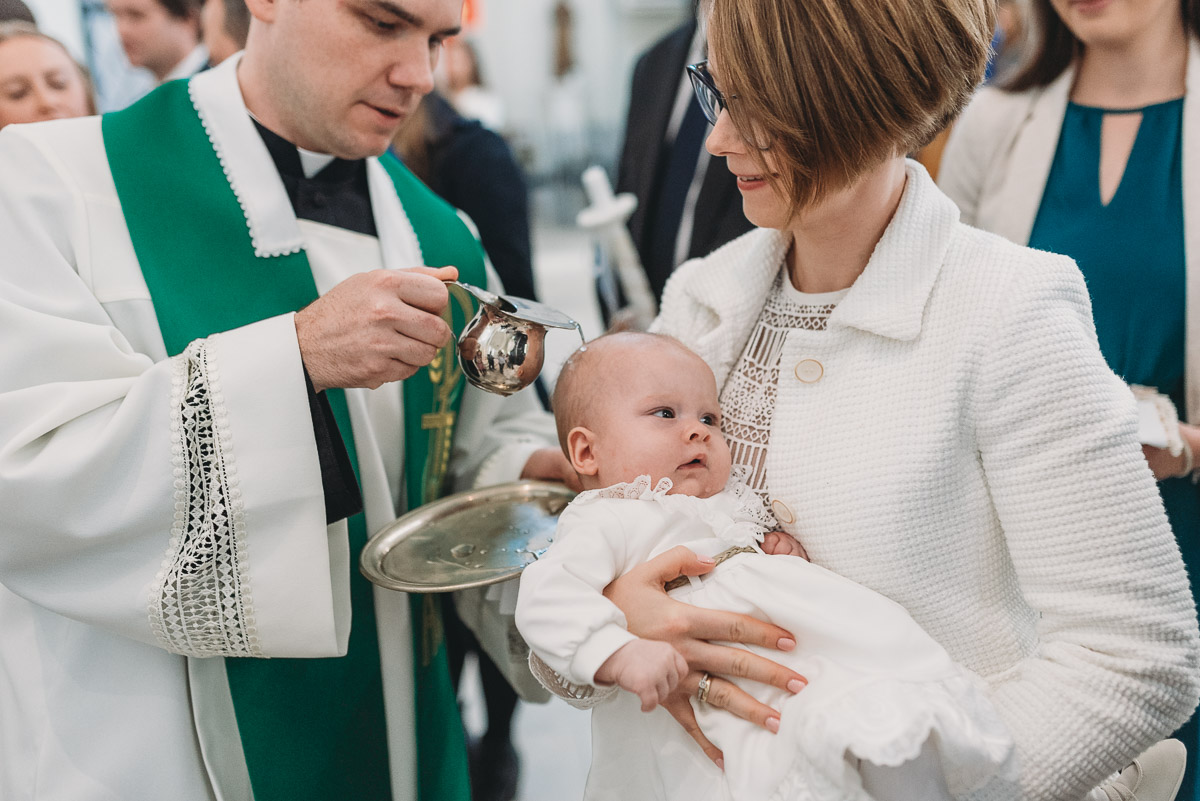 sakrament chrztu, ksiądz polewa główkę dziecka wodą święconą