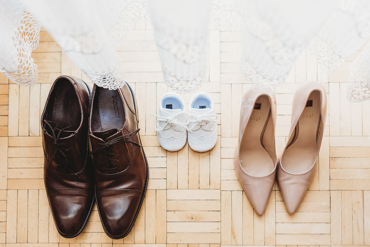 3 pary butów na podłodze, taty, mamy i dziecka w dniu chrztu