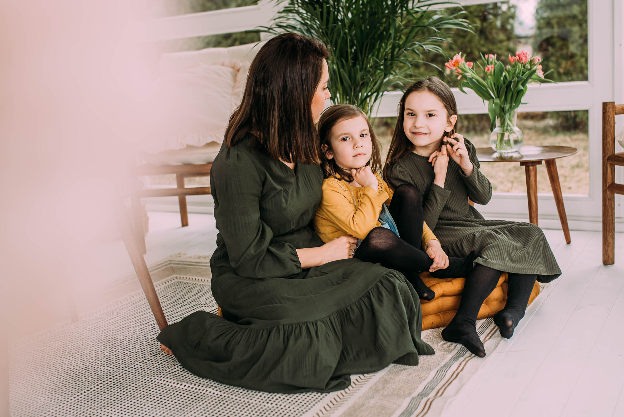 mama z dwoma córkami siedzi na dywanie