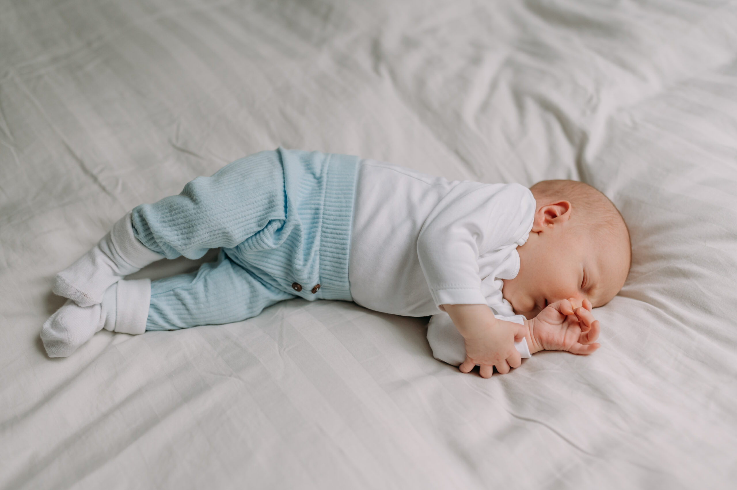 Dlaczego wybrałam naturalne sesje noworodkowe? Moja historia. niemowlę leży na łóżku