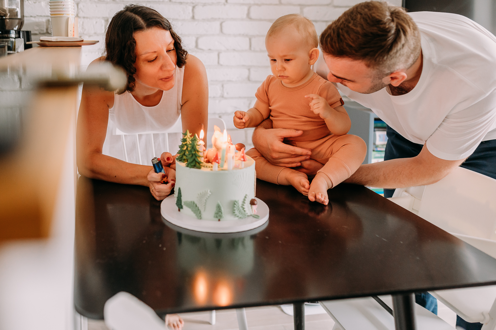 dziecko dmucha świeczki z rodzicami podczas roczku