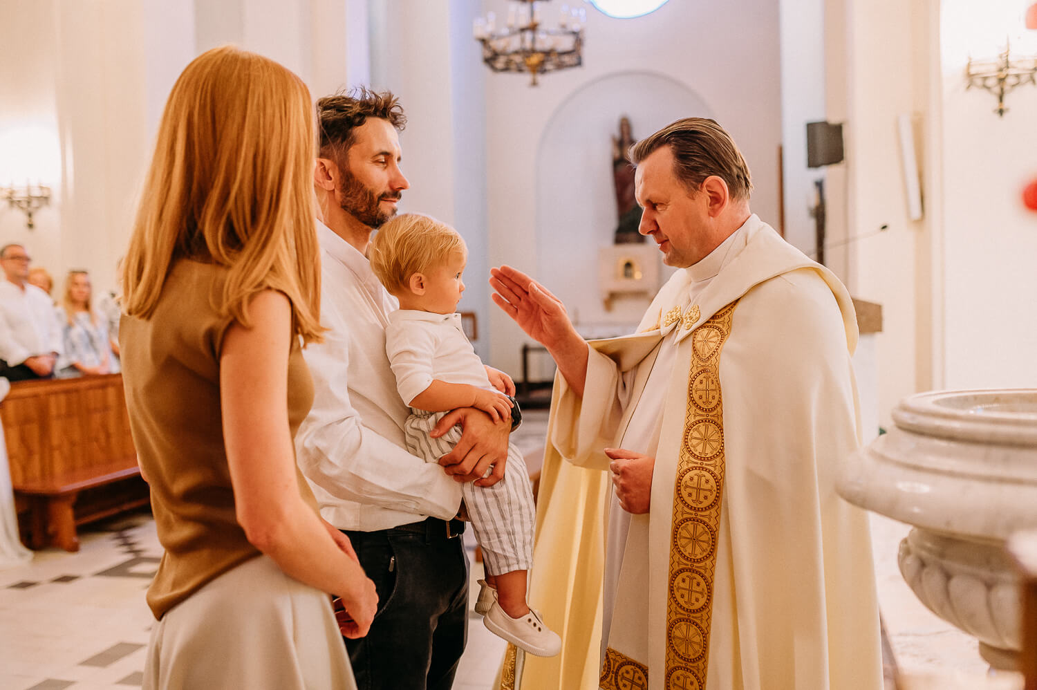 ksiądz robi dziecku znak krzyża podczas chrztu