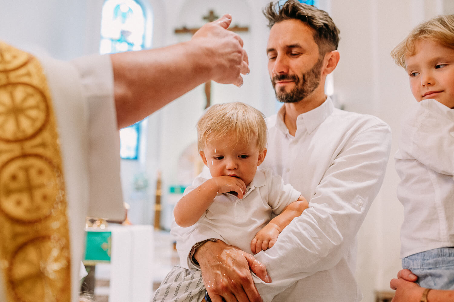 ksiądz polewa głowę dziecka podczas chrztu