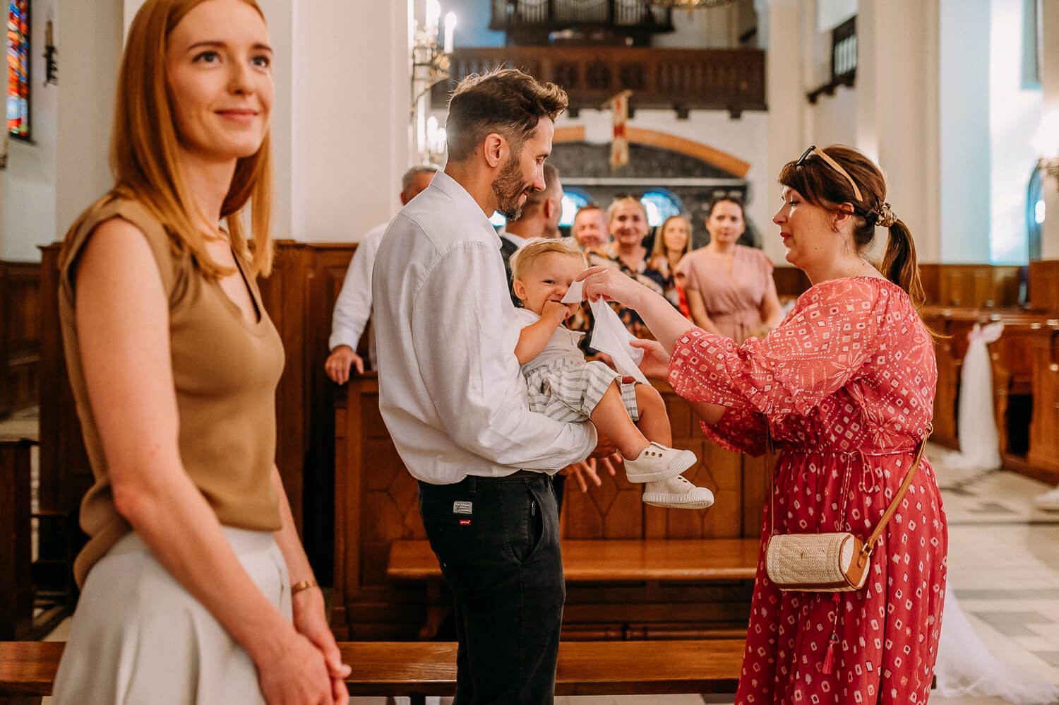 mama daje białą szatkę dziecku podczas chrztu