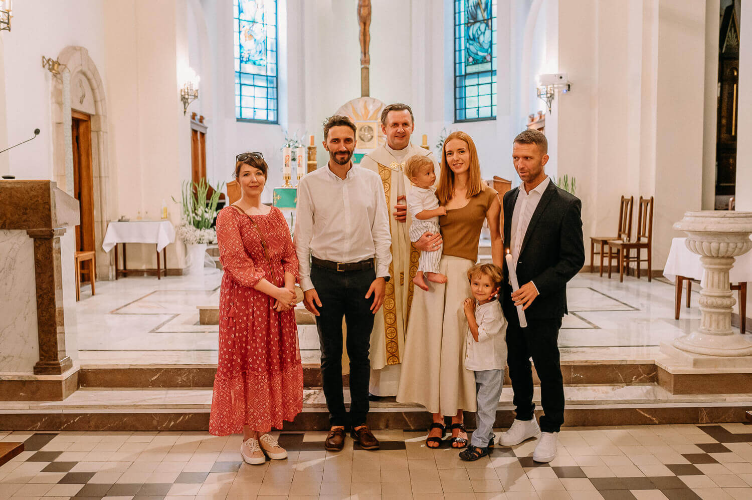 rodzice pozują do zdjęcia na tle ołtarza po chrzcie