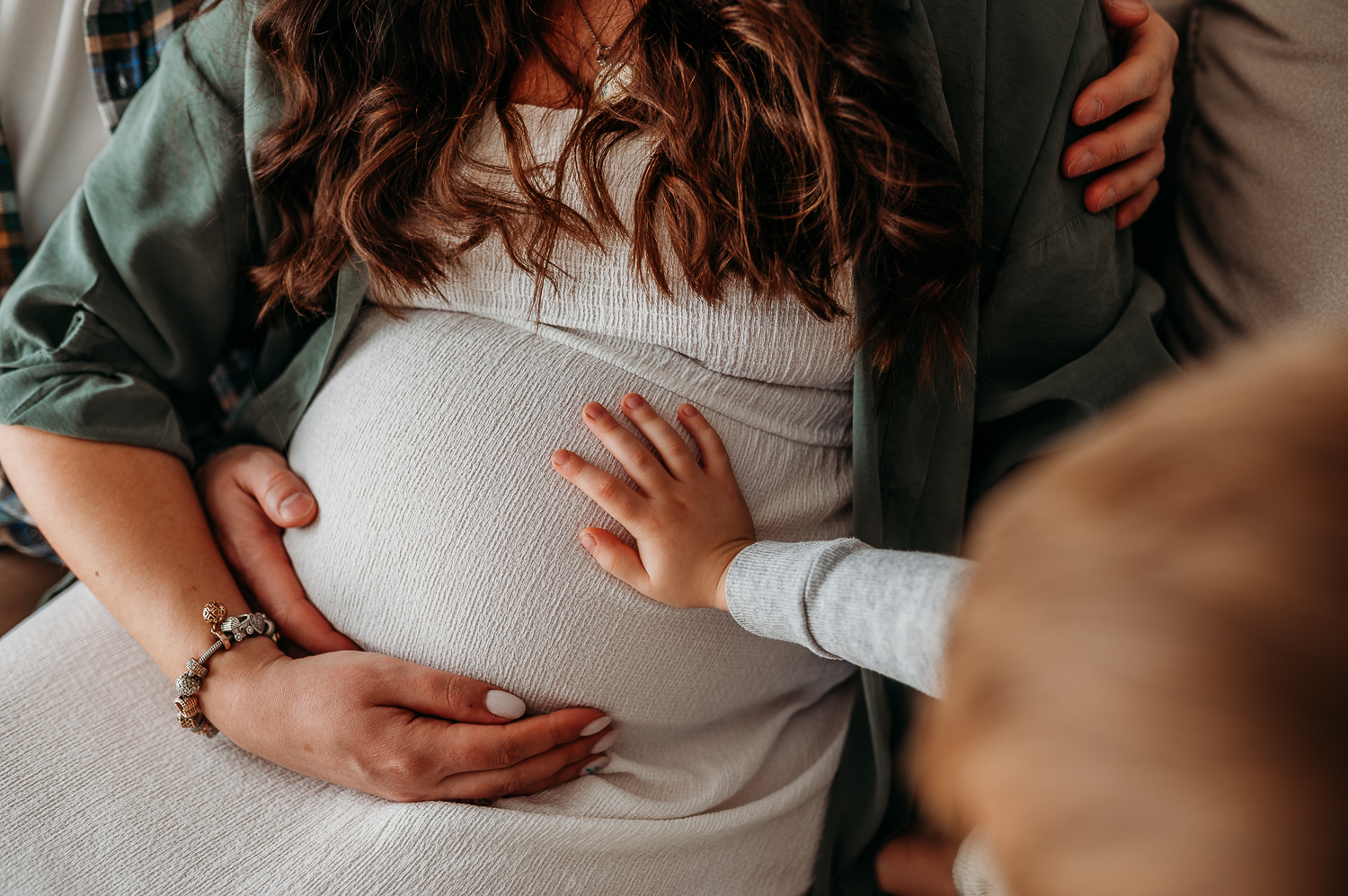 zdjęcie ciążowego brzuszka i małej rączki przyszłego brata. Jak wygląda sesja ciążowa? Najczęstsze pytania przyszłych mam