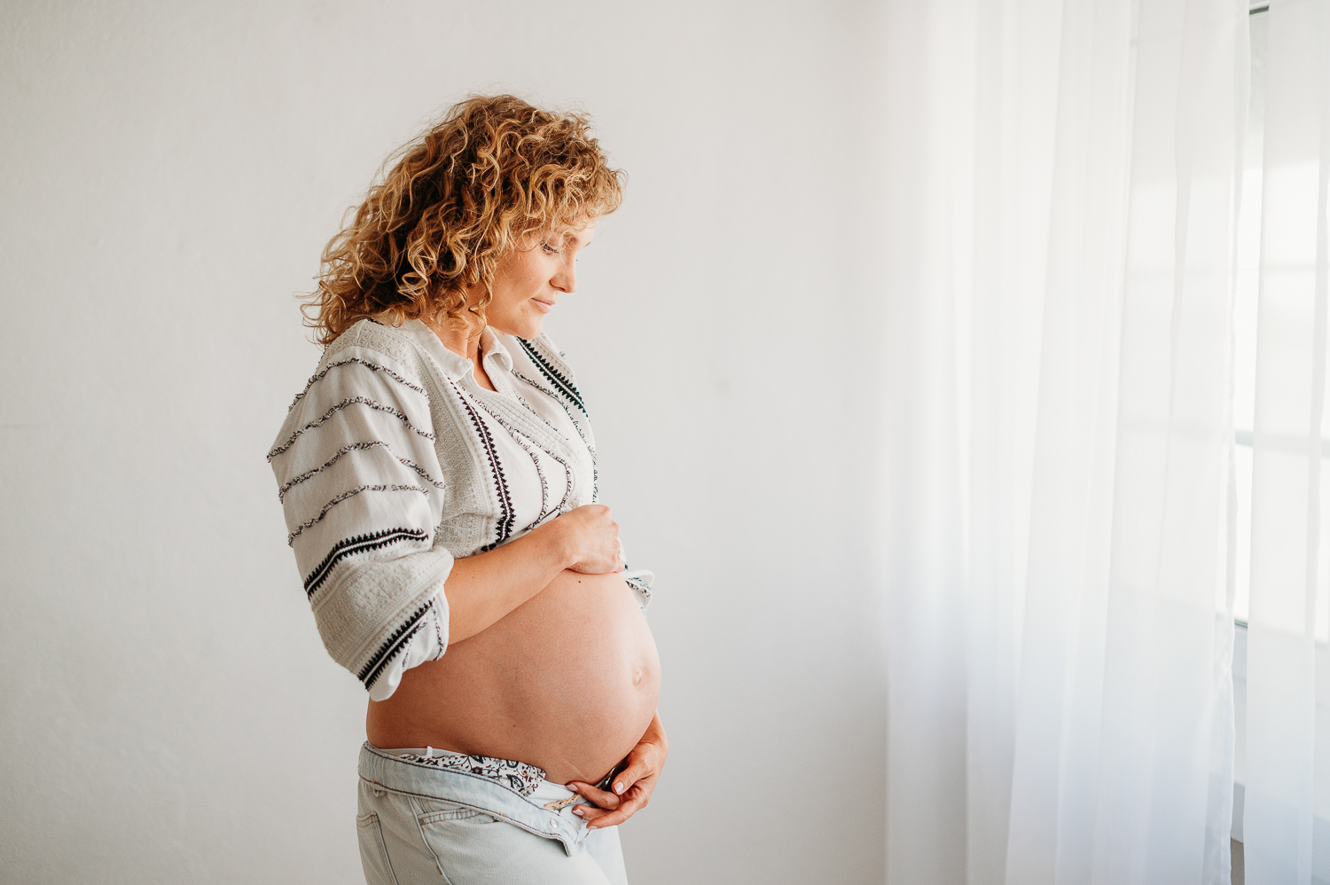 Najczęstsze pytania przyszłych mam, sesja minimalistyczna w studio, kobieta stoi w studio i pozuje do zdjęcia 