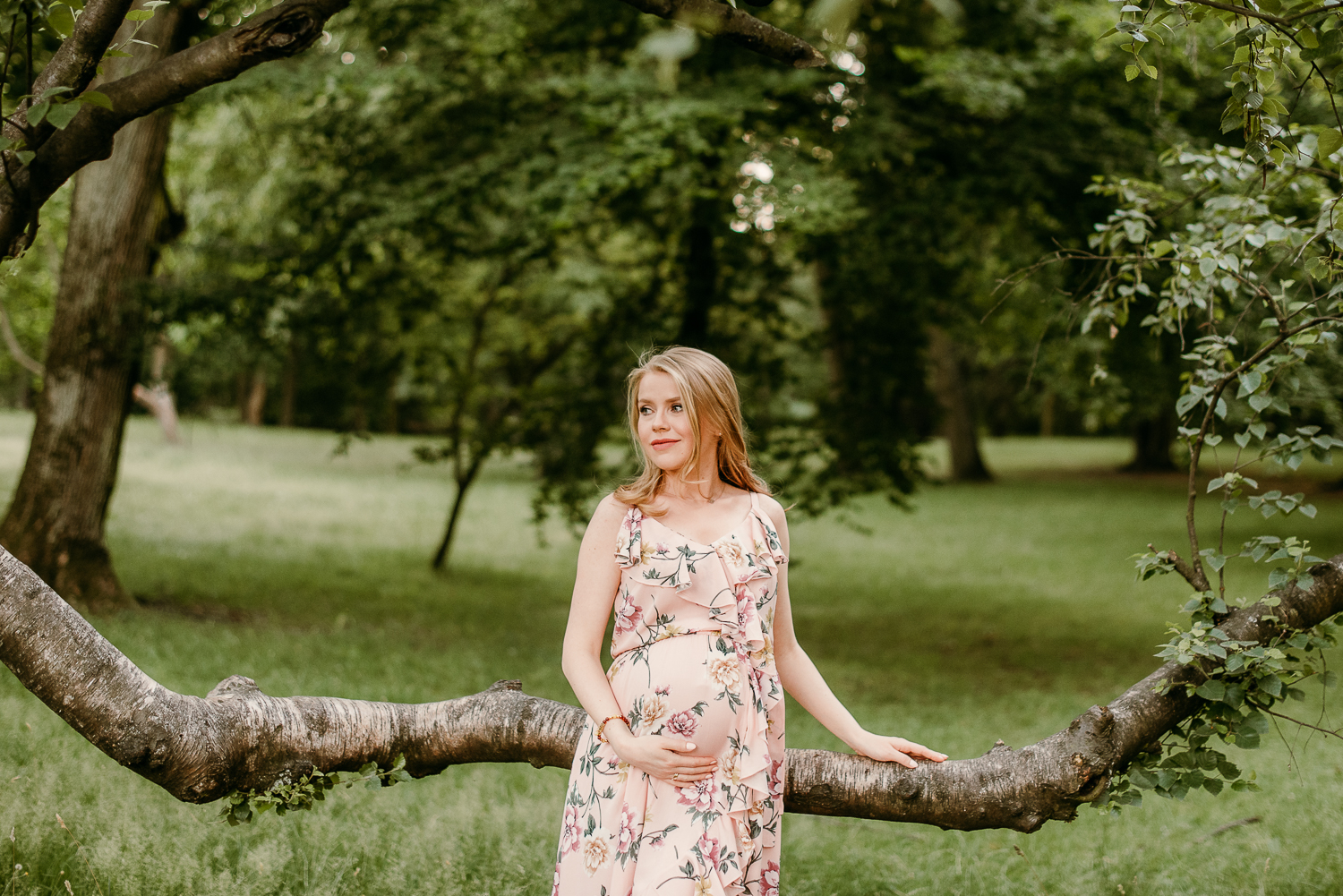 kobieta w ciąży stoi w parku i pozuje do zdjęcia