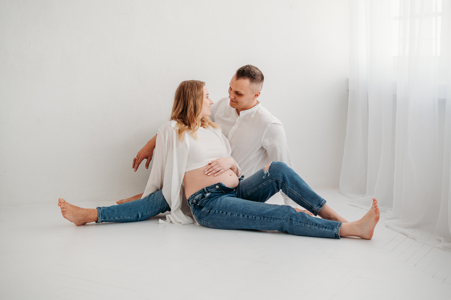 Sesja brzuszkowa w studio Warszawa, para w studio siedzi na przeciwko siebie