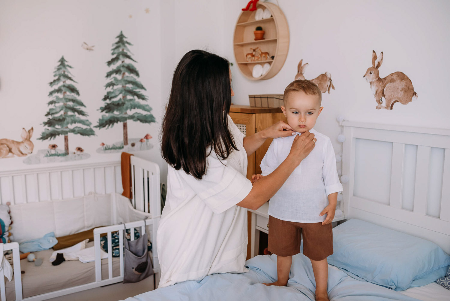 mama zapina dziecku koszule szykując do chrztu
