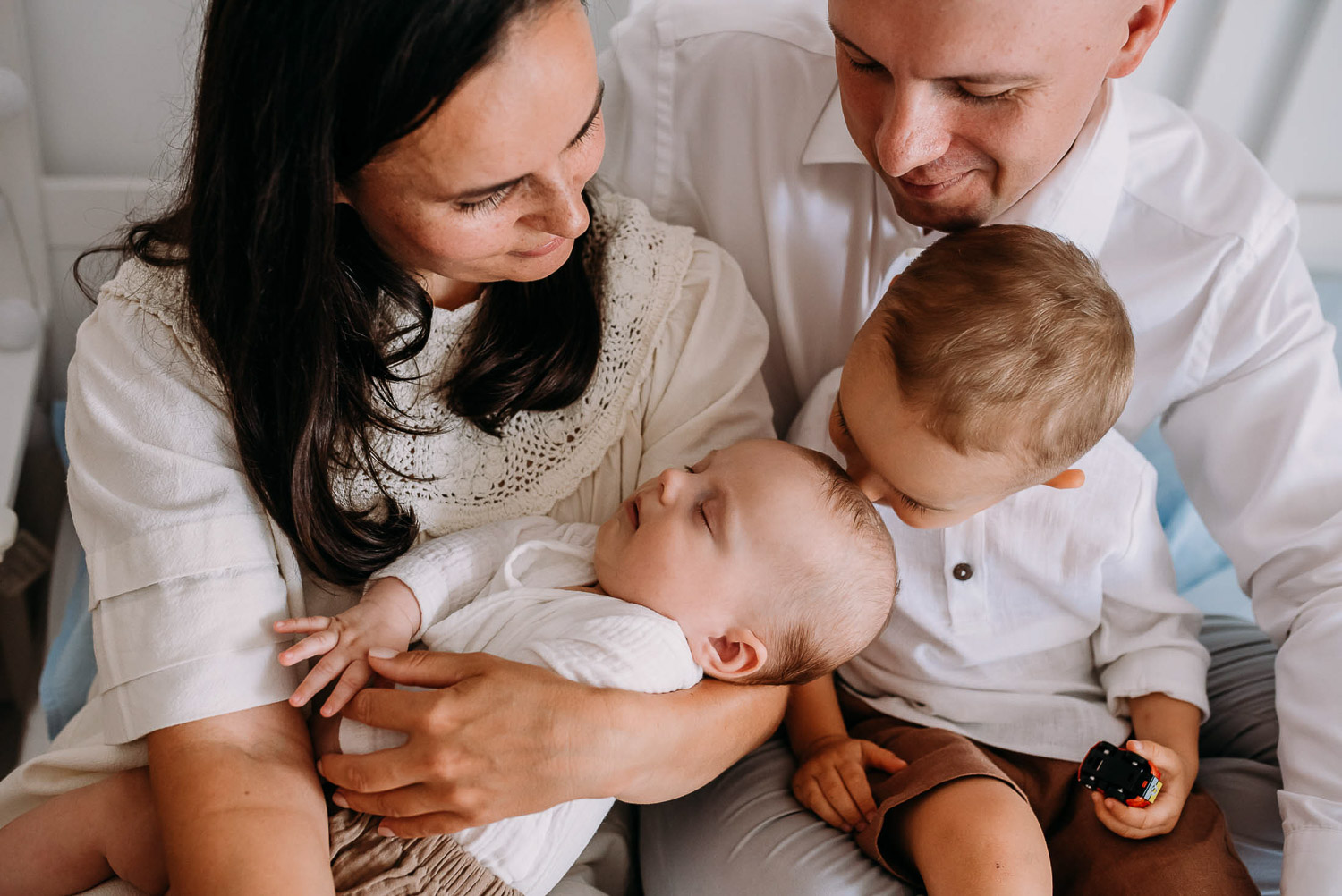 zdjęcie rodzinne na którym starszy brat całuje młodszego brata w głowę 