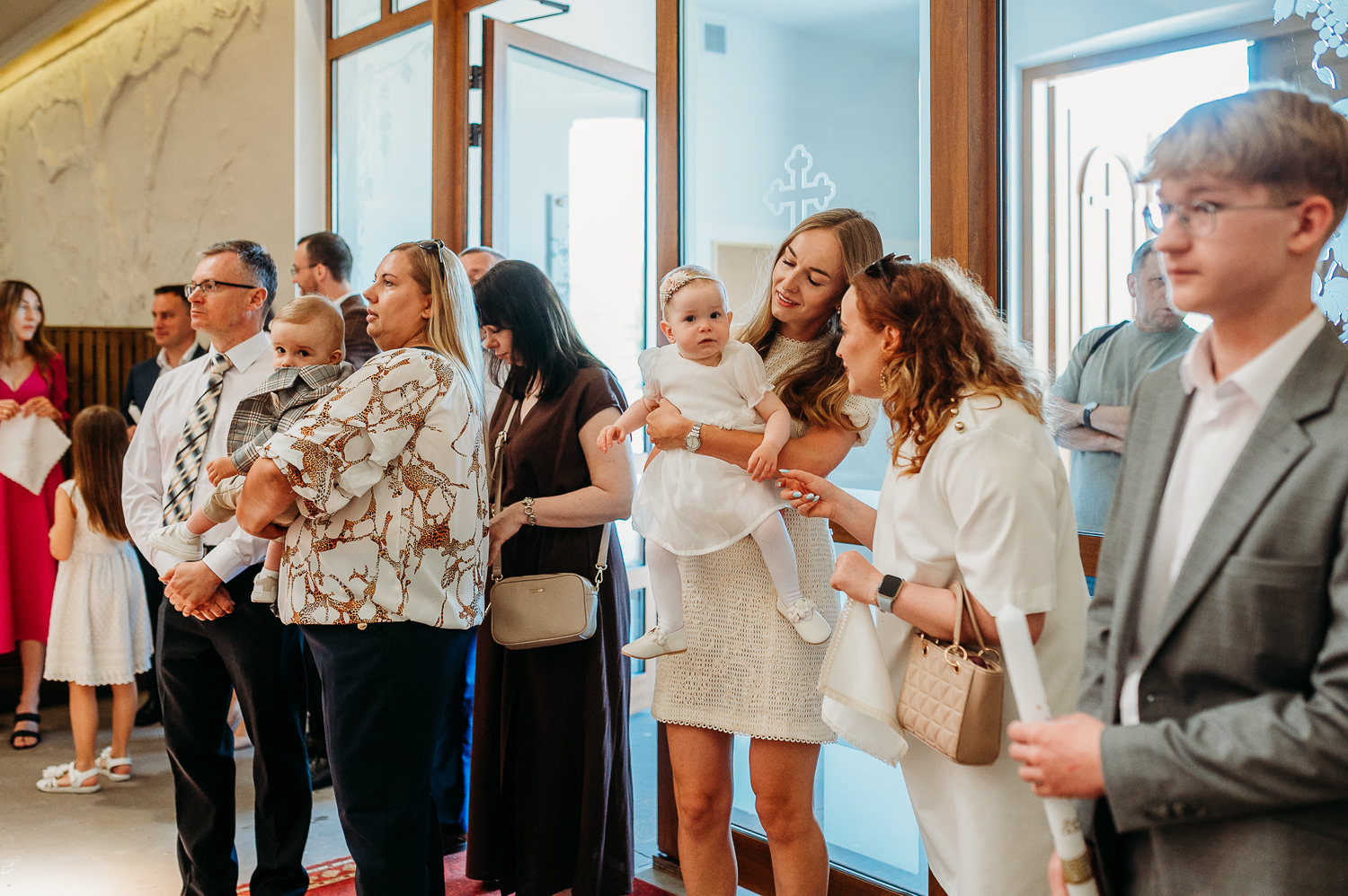 rodzice i chrzestni stoją pod organami i czekają na księdza podczas reportażu z chrztu w warszawie