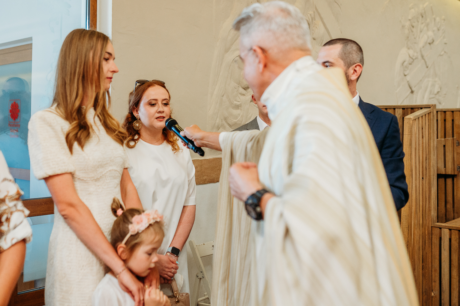 rodzice i chrzestni stoją pod organami i czekają na księdza podczas reportażu z chrztu w warszawie