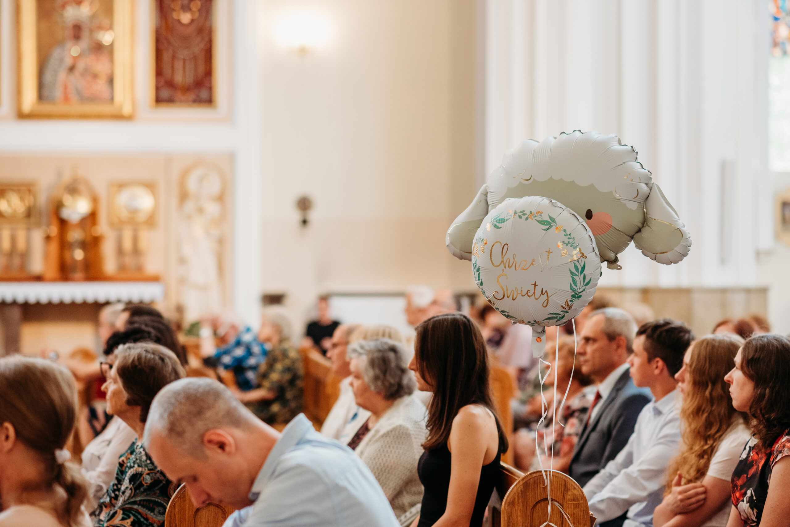 zdjęcie zrobione podczas mszy w kościele w tle widać balon z napisem chrzest święty