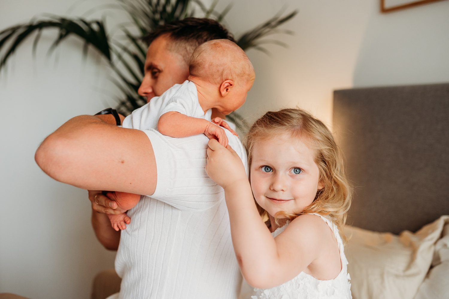 starsza siostra trzyma za rączkę noworodka 