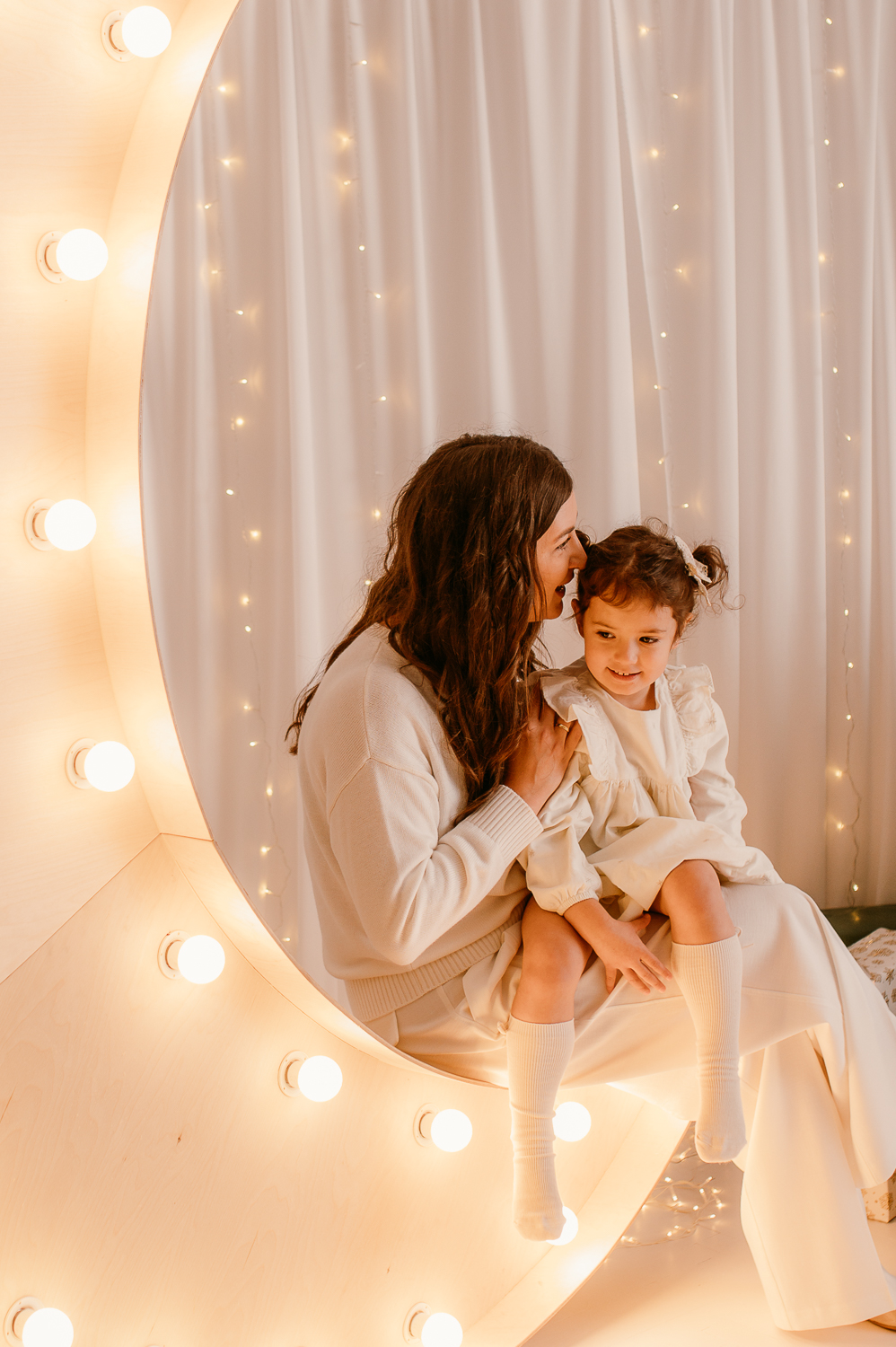 Mama z córką siedzą na wielkim księżycu podczas sesji świątecznej w warszawie