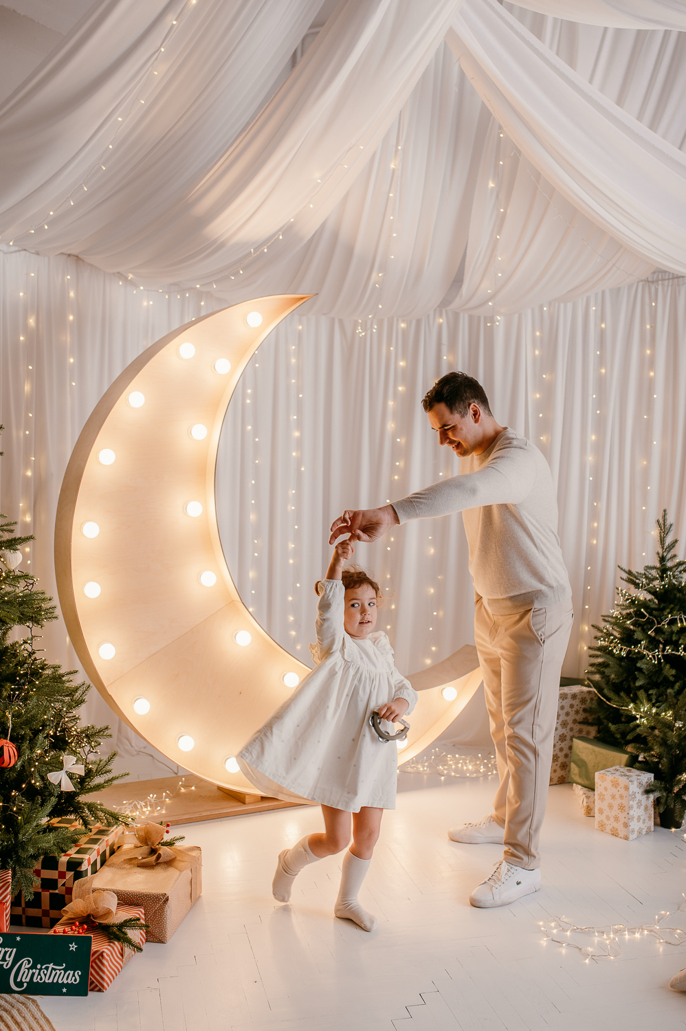 tata kręci córeczkę około na palcu podczas sesji świątecznej