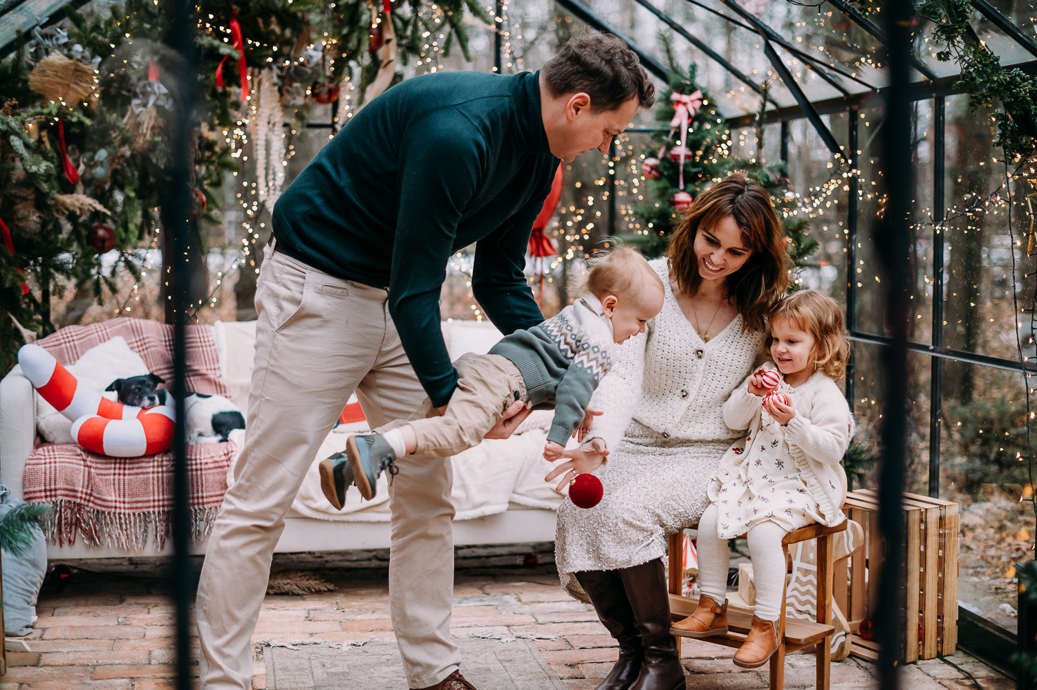 rodzina siedzi w szklarni podczas sesji świątecznej