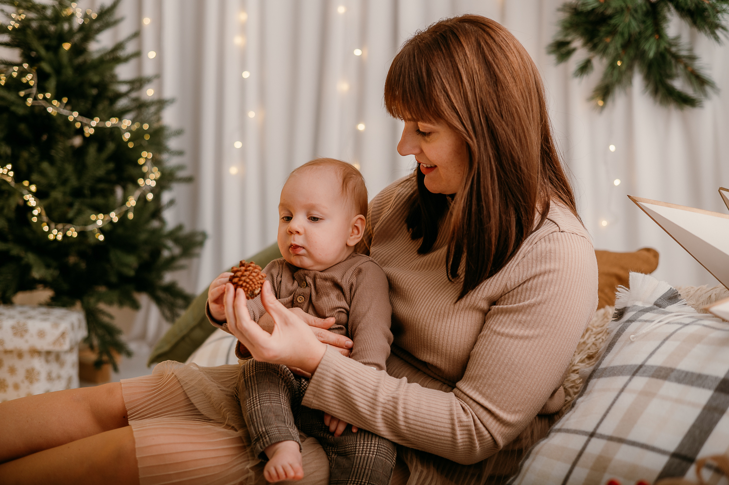mama siedzi z małym dzieckiem i pokazuje mu szyszkę
