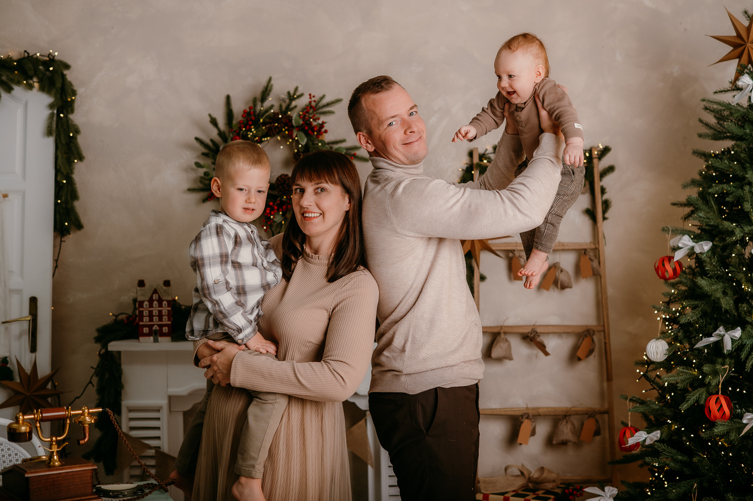 rodzina stoi na tle świątecznej aranżacji w studio z wieloma świątecznymi dodatkami<br />
