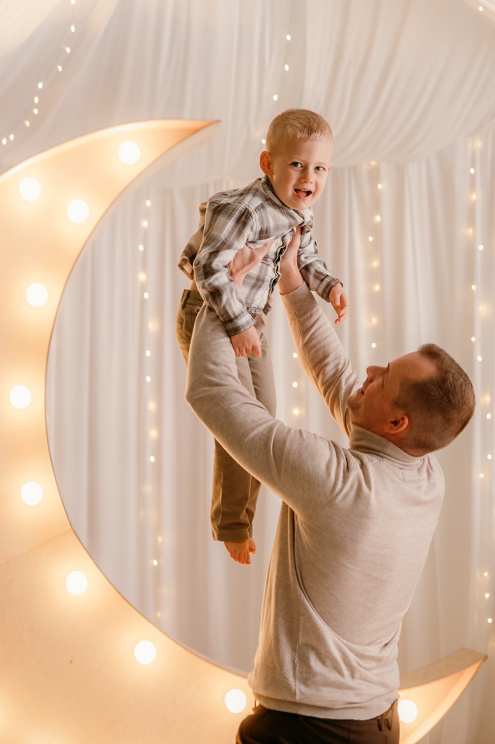 tata podnosi dziecko do góry na tle świecącego księżyca