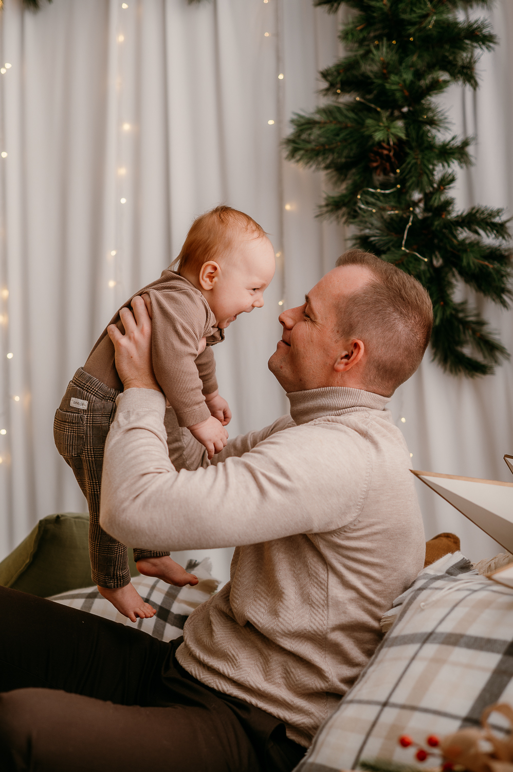 tata podnosi małe dziecko do góry i uśmiecha się do niego 