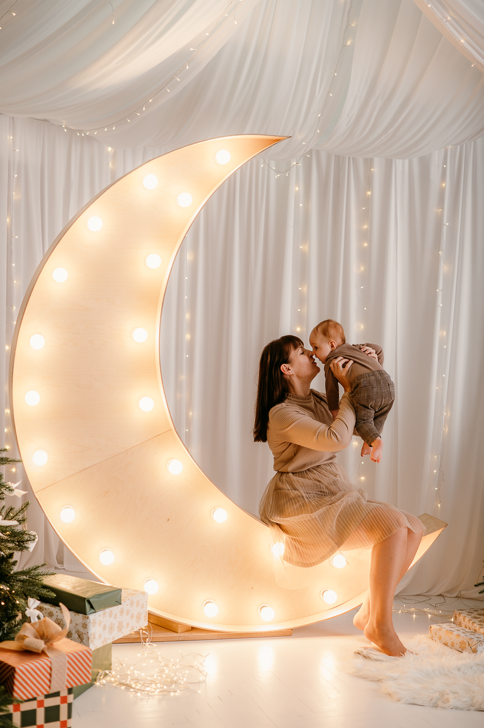 mama siedzi na świecącym księżycu i podnosi dziecko do góry