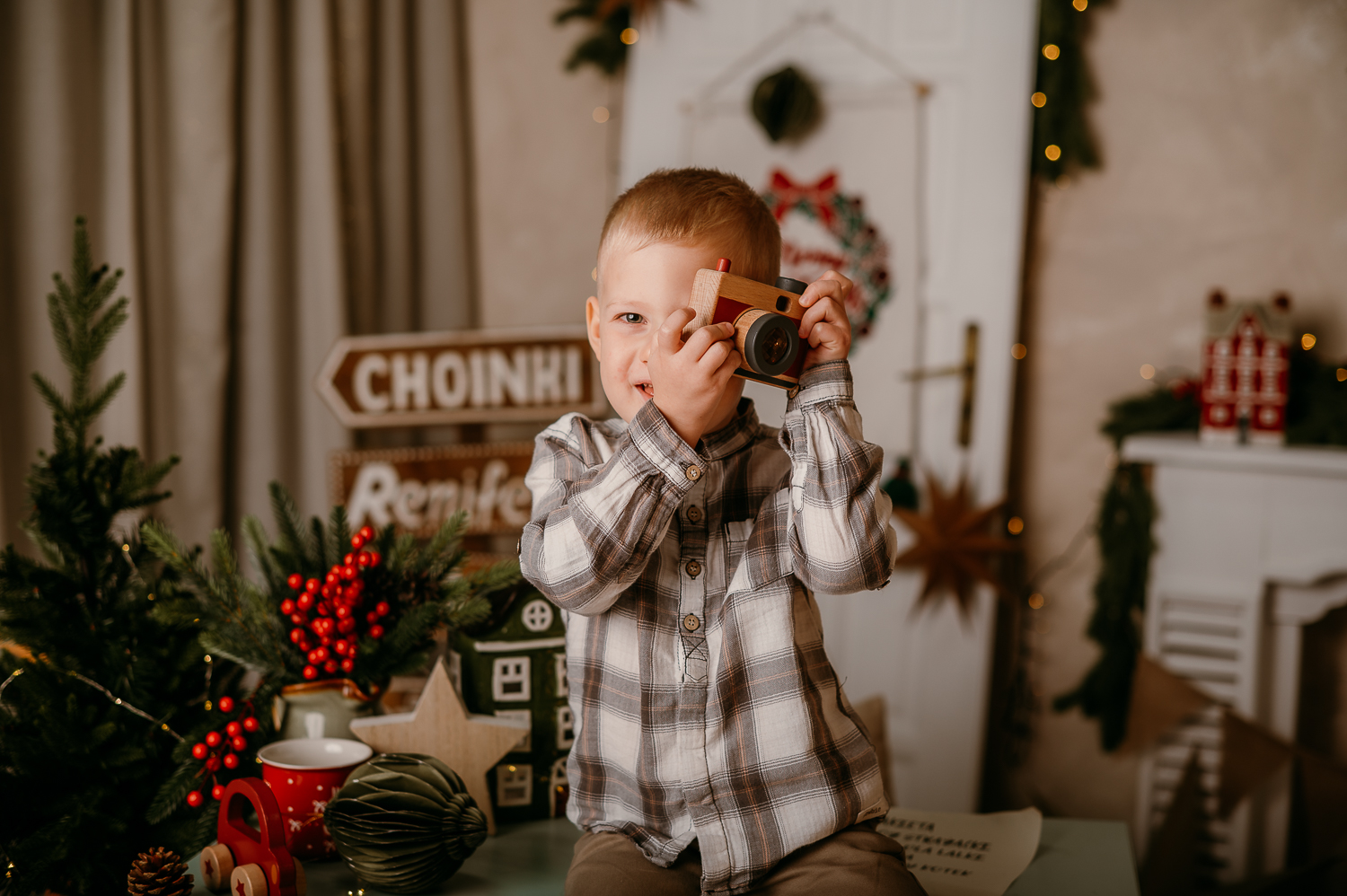 sesja świąteczna warszawa-4 mały chłopie stoi na stole i robi zdjęcie zabawkowym drewnianym aparatem
