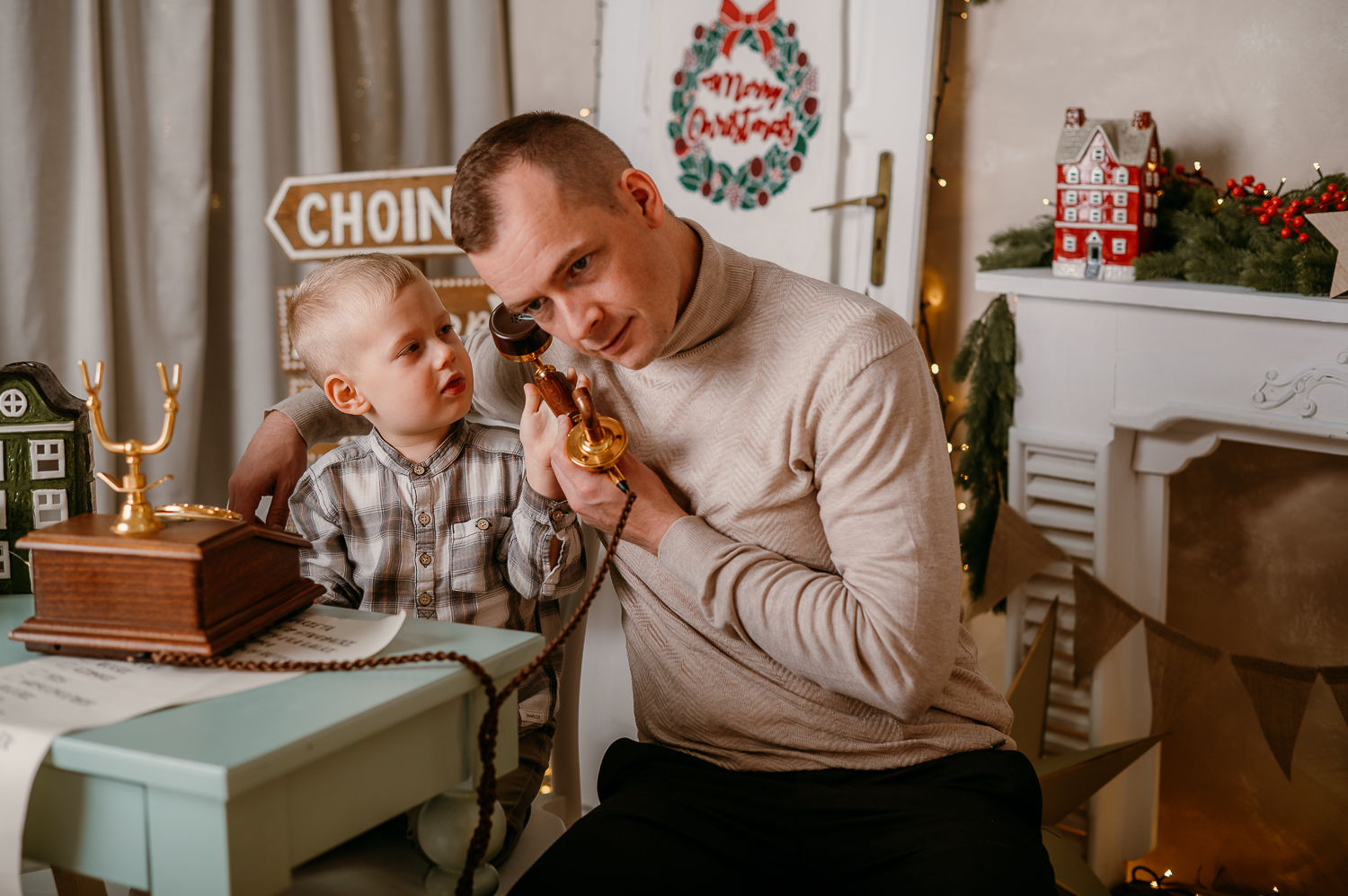tata siedzi przy stole z dzieckiem i udaje ze dzwoni przez zabytkowy aparat