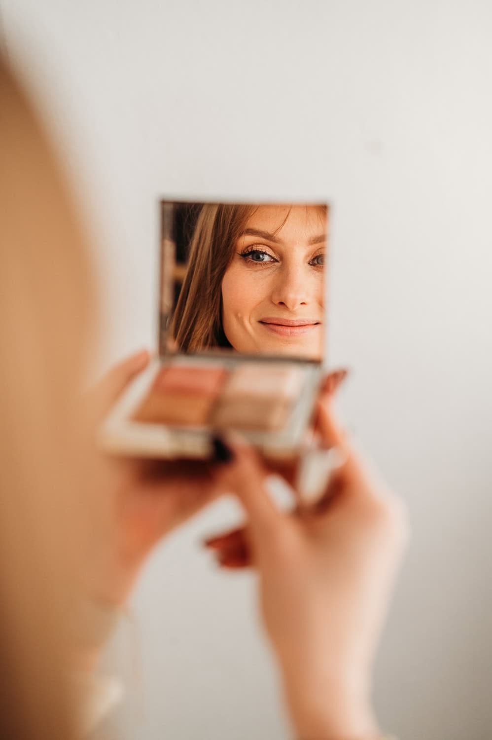 kobieta patrzy w lusterko i robi makijaż do sesji zdjęciowej w warszawie