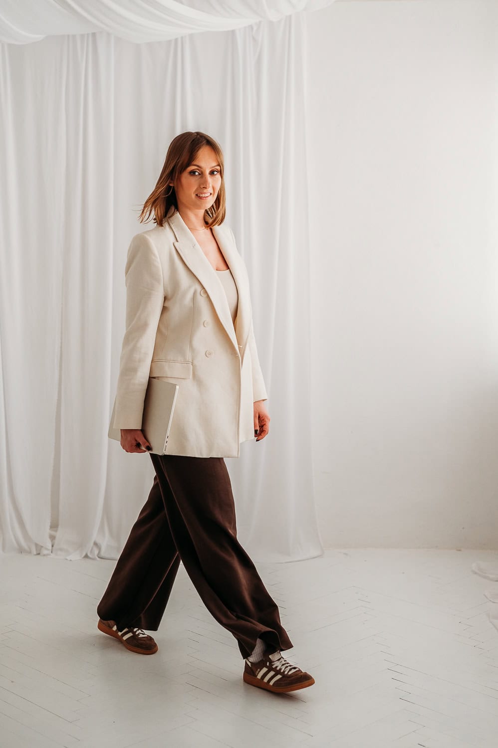 kobieta idzie z laptopem w ręku podczas sesji wizerunkowej