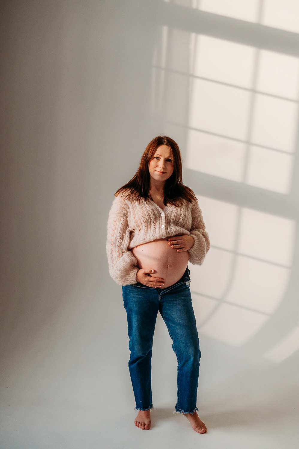 dziewczyna w ciąży stoi w moherowym sweterku i pozuje do zdjęć