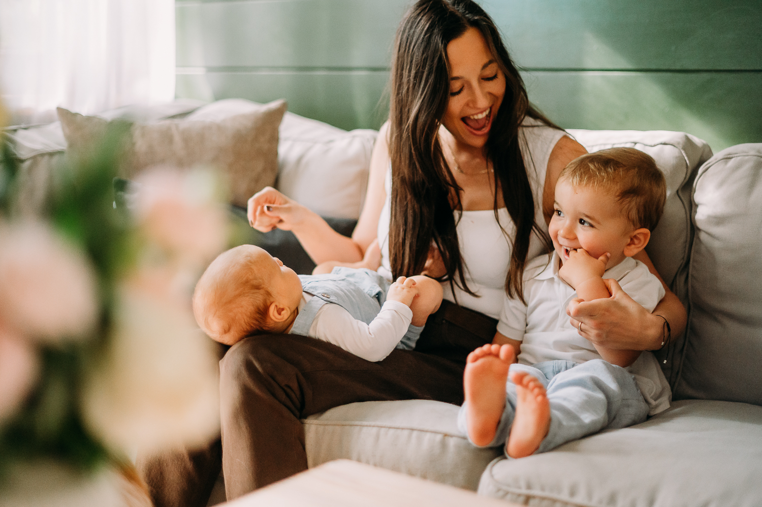 mama z dwójką małych dzieci siedzi na kanapie i śmieje się