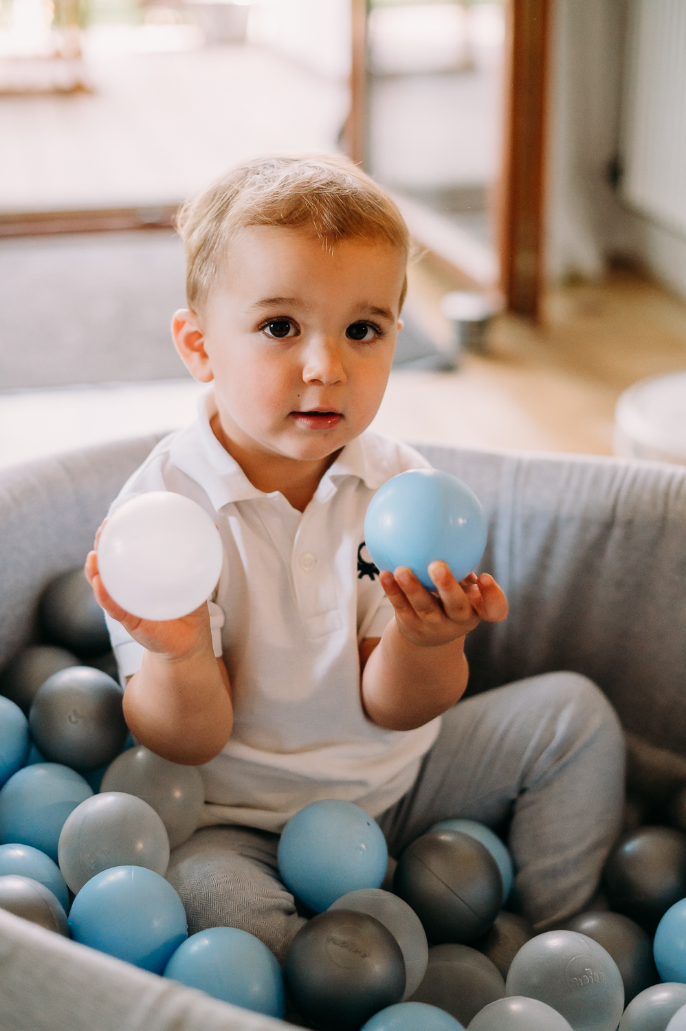 chłopiec siedzi w baseniku z piłeczkami i bawi się podczas naturalnej sesji zdjęciowej z dzieckiem w warszawie