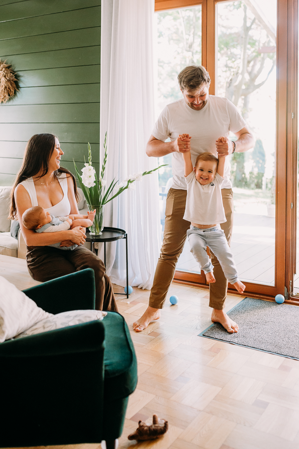 mama siedzi z maluchem a tata chustą starsze dziecko podczas sesji rodzinnej