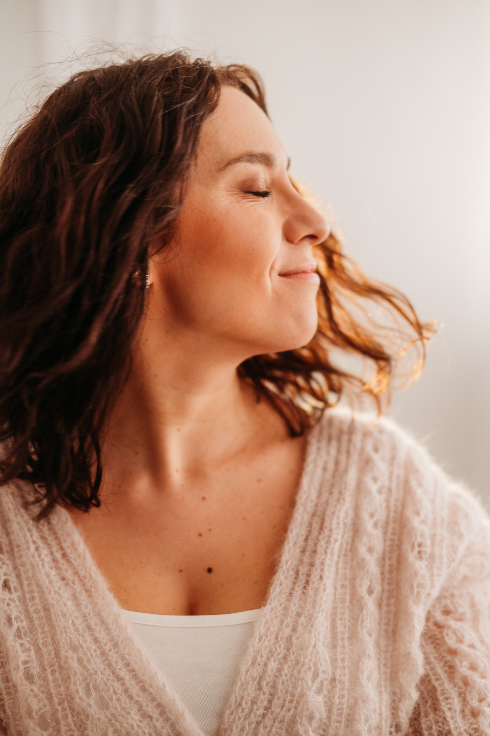 kobieta w moherowym jasno różowym swetrze ma zamknięte oczy i potrząsa głową